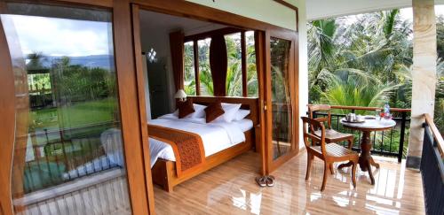 MayongThe Aroma Villa Munduk的一间卧室配有一张床,阳台配有桌子