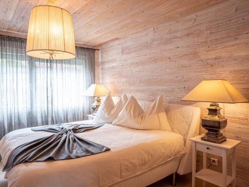 圣莫里茨苏尔瓦尔3号两卧室公寓的一间卧室配有一张白色的床、木墙和两盏灯。