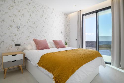 蒂亚斯Villa Ainara的一间卧室配有一张带黄色毯子和窗户的床