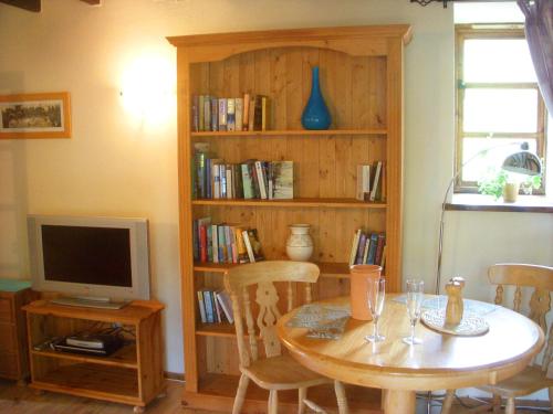 StokeinteignheadThe Nest - Thatched seaside country cottage for two的一间设有桌子、电视和书架的房间