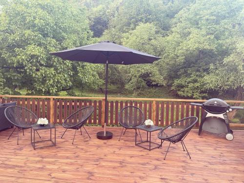 加布罗沃Guest house Mikaela的一个带椅子和遮阳伞的庭院以及烧烤设施。