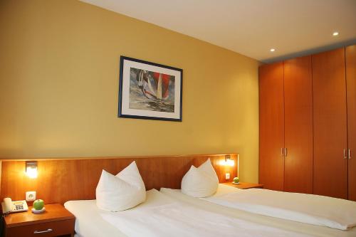 罗斯托克威尔第酒店的配有白色枕头的床的酒店客房