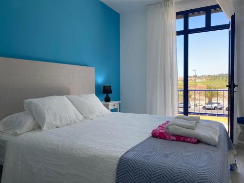 梅罗那瑞斯Bahia Meloneras Vista Golf的一间卧室配有一张蓝色墙壁和窗户的床