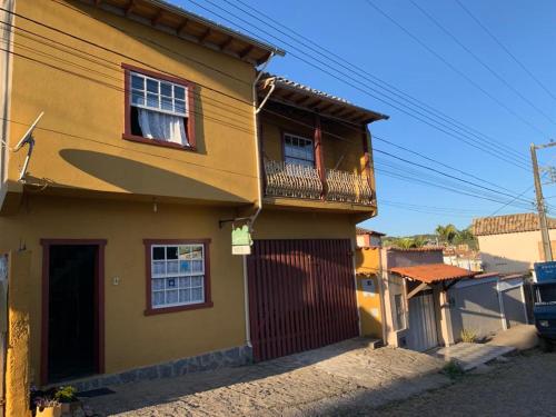 蒂拉登特斯Hostel Lumiar da Serra的阳台的黄色房子,带冲浪板