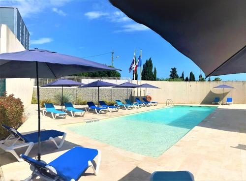 蒙彼利埃蒙彼利埃奥德修姆智选假日酒店的一个带蓝色椅子和遮阳伞的游泳池