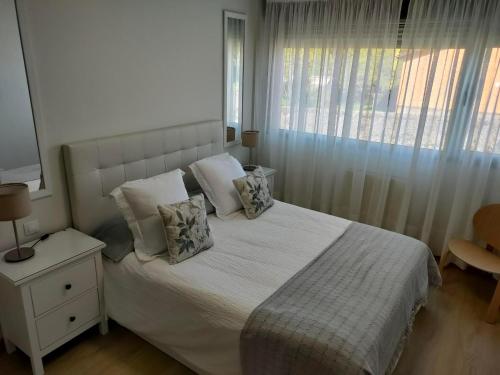 利亚内斯Apartamentos Boutique Arquera Golf I的卧室配有带枕头的白色床和窗户。