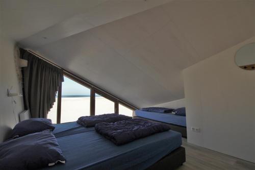 弗劳温普尔德Breezand Beachhouses的带大窗户的客房内的两张床
