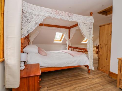 金斯林Little Lodge的卧室配有带白色窗帘的天蓬床