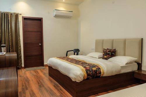 阿姆利则De Manora Homes - Unpretentious hotel with a garden , posh area Ranjit Avenue的一间卧室设有一张大床,铺有木地板