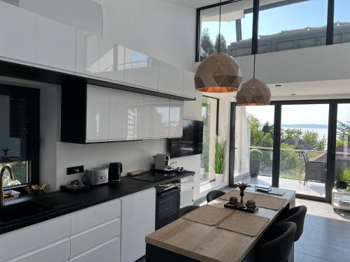 鲍洛通维拉戈什ARIS Apartman的厨房配有白色橱柜和木桌