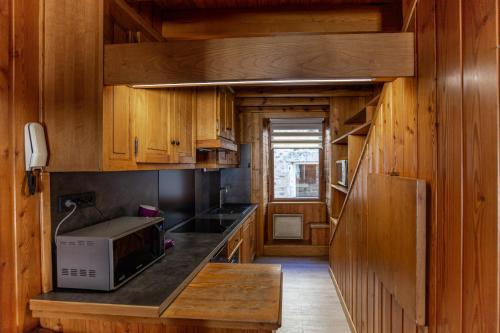 朗戈涅La Cabane du Petit Tour的一间带木制橱柜和微波炉的厨房