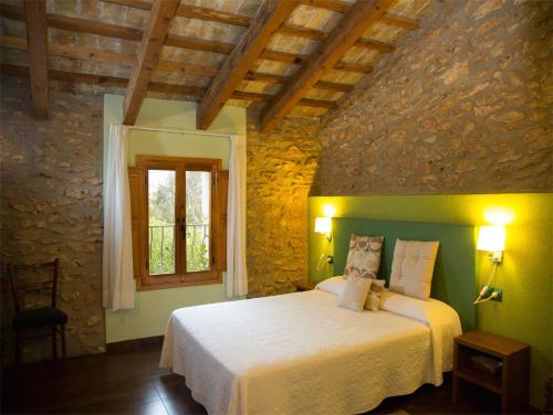 L'Aldea马斯马斯多旅馆的卧室配有石墙内的白色床