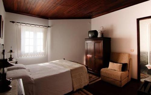 皮奥达Casa da Padaria的卧室配有床、椅子和窗户。
