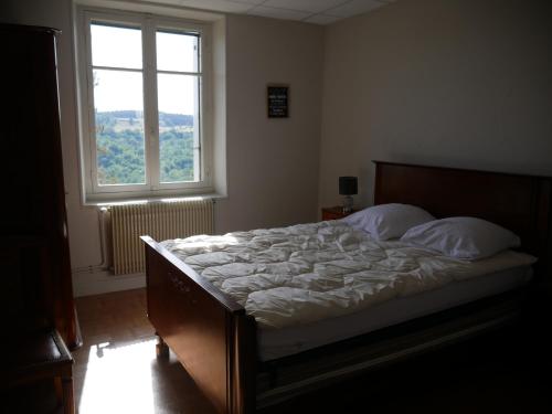 PolignacCHEZ GRAND MAMIE的卧室内的一张床铺,设有大窗户