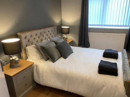 科尔温湾Pendle House Apartment 1的一间卧室配有一张带枕头的床和两盏灯。