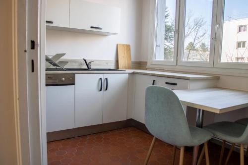 波城La Fabrique Paloise的厨房配有白色橱柜和桌椅