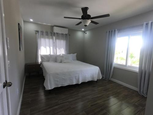 罗阿坦Single-Family Home With Gated Tropical Yard的卧室配有白色的床和吊扇