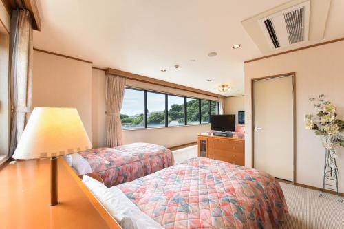 壹岐市壹岐玛丽娜酒店的一间卧室设有两张床和窗户。