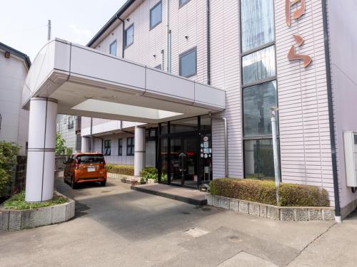 KinoshitaTabist Business Ryokan Fukihara Ina Ihoku的停在大楼前的橙色汽车
