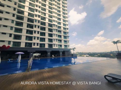 加影Aurora Vista Homestay Bangi at Vista Bangi With WIFI NETFLIX GYM SAUNA COWAY SWIMMING POOL-RIVER VIEW的一座大型建筑,在一座建筑前设有一个游泳池