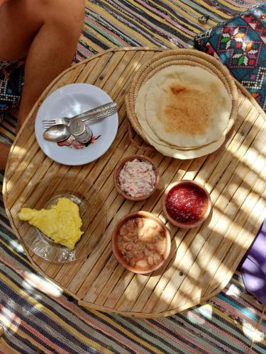 锡瓦Forest Camp Siwa - كامب الغابة的木桌,上面放有盘子和碗的食物