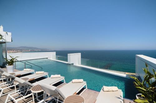 巴达洛纳Hotel Marina Badalona的一个带白色躺椅的游泳池以及大海
