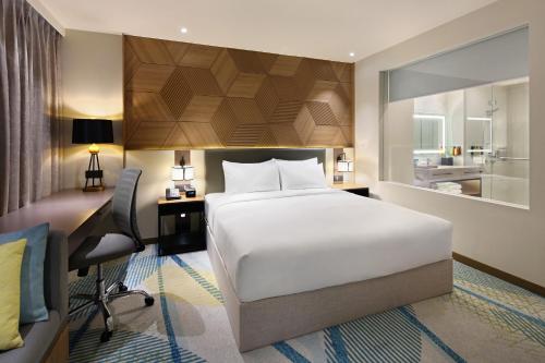 宿务Holiday Inn Cebu City, an IHG Hotel的卧室配有一张白色大床、一张桌子和一把椅子
