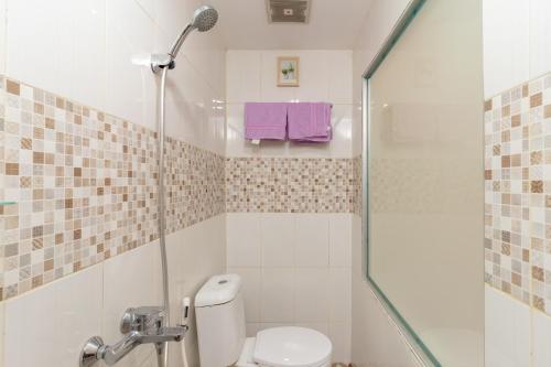 雅加达RedDoorz Plus Near RS Royal Taruma Grogol的浴室设有卫生间和带紫色毛巾的淋浴。