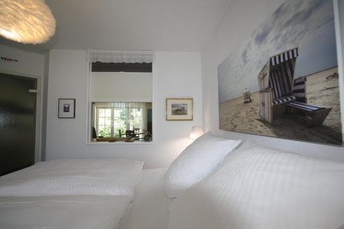 圣彼得奥尔丁Ferienwohnung "Zum Böhler Leuchtturm"的白色的卧室配有一张床,墙上挂着一幅画