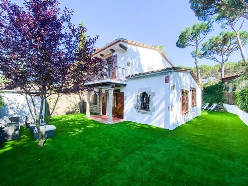 圣塔克里斯蒂纳阿鲁Villa en el Golf Costa Brava a 5 min de la playa的白色的房子,有绿草的院子