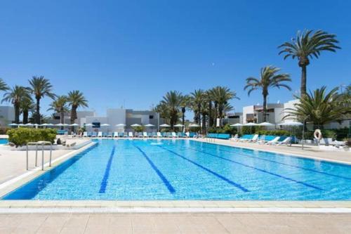 阿罗纳Primavera appartement tot 7 personen的度假村内一座种有棕榈树的大型游泳池