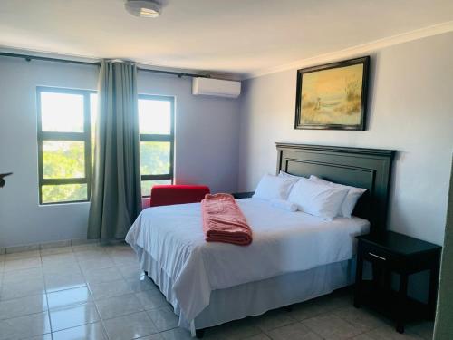 理查兹湾Xaba Guest Lodge的一间卧室配有一张床铺,床上铺有红色毯子