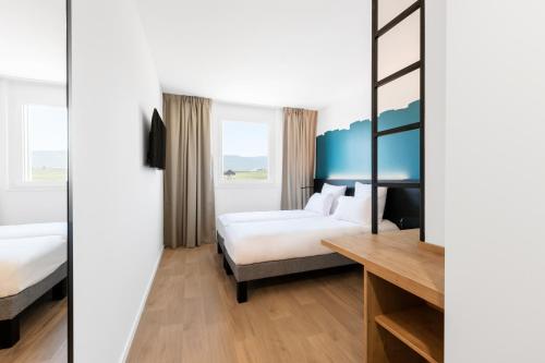 尼翁B&B HOTEL Nyon的酒店客房设有两张床和一张桌子。