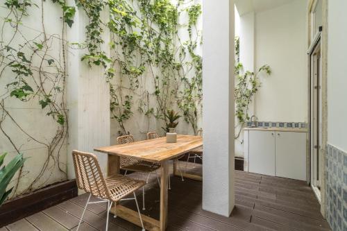 里斯本Casa Boma Lisboa - Design Apartment with Private Vegetal Terrace - Lapa VII的桌子和椅子,墙上有植物