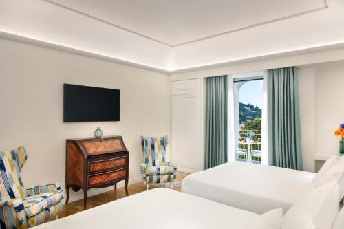 卡普里Pazziella Garden & Suites的酒店客房设有两张床、一张书桌和一个窗户。