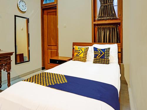 玛琅SPOT ON 91530 Sumpil Syariah的一间卧室配有两张带黄色和蓝色枕头的床