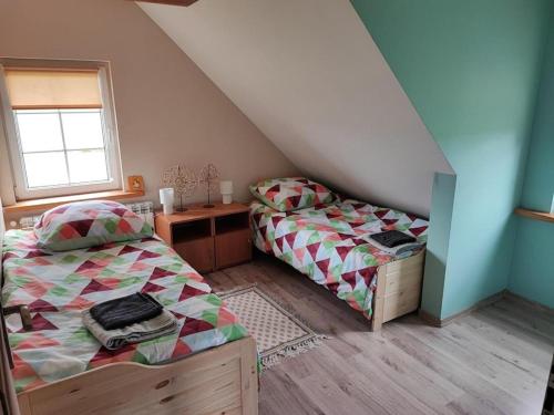 Domek nad stawem的一间卧室设有两张床、一张桌子和一个窗口。