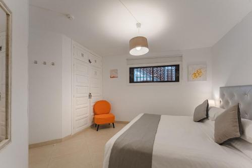 洛斯克里斯蒂亚诺斯LosCristianos Front Line of Ocean WiFi的一间卧室配有一张床和一张橙色椅子