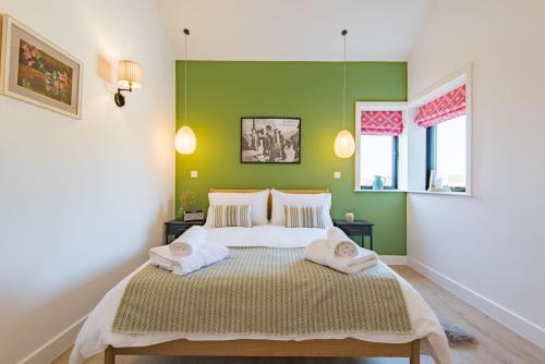 StalisfieldThe Parlour by Bloom Stays的一间卧室设有绿色的墙壁和一张带两个枕头的床
