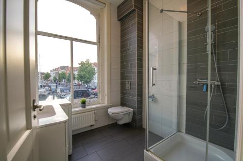 莱顿2L De Volharding的带淋浴和卫生间的浴室以及窗户。