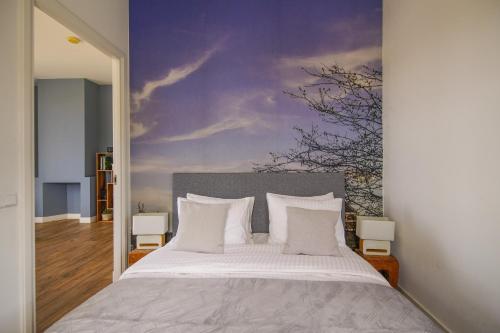 莱顿2L De Volharding的卧室配有一张大床,墙上挂有绘画作品