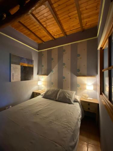 CambreAgradable chalet rústico的一间卧室设有床、两张桌子和一扇窗户