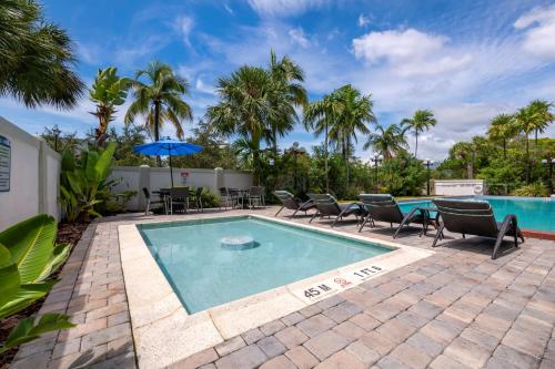 北迈阿密Best Western Plus North Miami-Bal Harbour的一个带椅子和桌子的游泳池以及一把遮阳伞