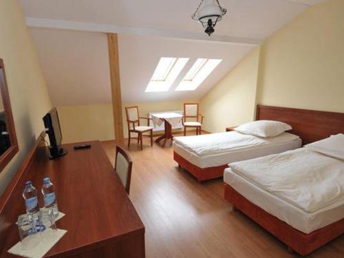 可罗日采玛格达宾馆的酒店客房带两张床和一张桌子以及椅子。