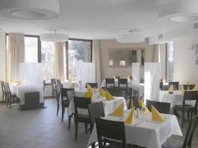 Murrhardt索纳帕斯特餐厅酒店的餐厅设有桌椅,配有黄色餐巾