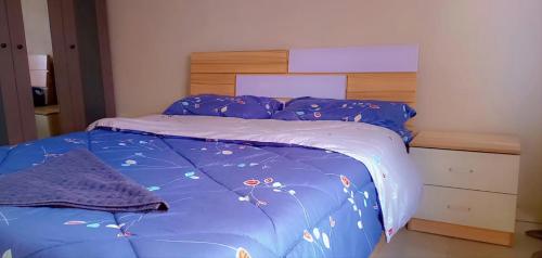 ChililabombweFully Furnished Apartment in Chililabombwe的一张带蓝色棉被和木制床头板的床