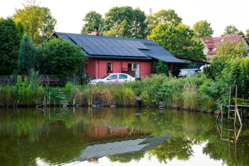 卢巴夫卡Stanica pod Zadzierną Domki całoroczne的水体旁的红色房子