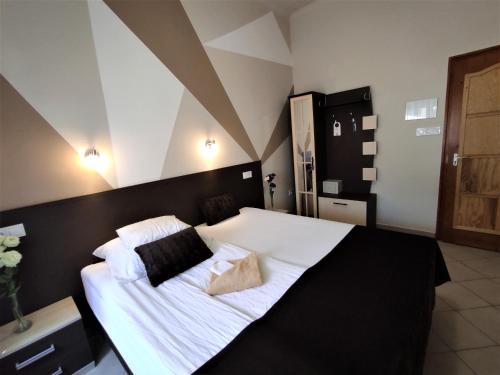 毛科Oázis Panzió的卧室配有一张带白色床单和枕头的大床。