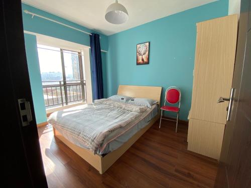 昆明合家欢的一间拥有蓝色墙壁的卧室,配有一张床和红色椅子