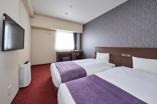 札幌Hotel Axia Inn Sapporo Susukino的酒店客房设有两张床和一台平面电视。